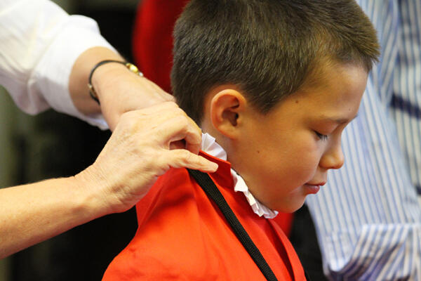 Chorister Nathanael Wain holds still while his robe is adjusted.