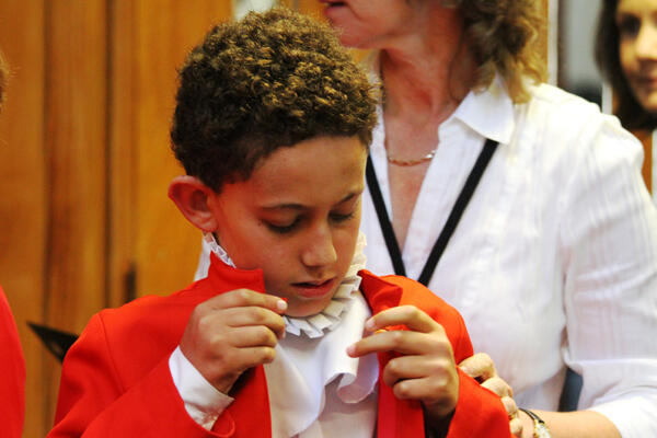Now this hooks on to that, and the other tucks in here... Chorister William Pegg dresses for the memorial service.