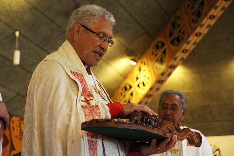 Bishop Ngarahu blesses the hoe carved by Rei Mihaere that was presented to him.