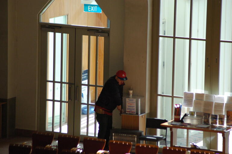 A man helps himself to cash from the cathedral offertory box.