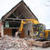The excavator drags the fallen bricks of the Churchill Courts chapel into a pile, ready to be carted away.