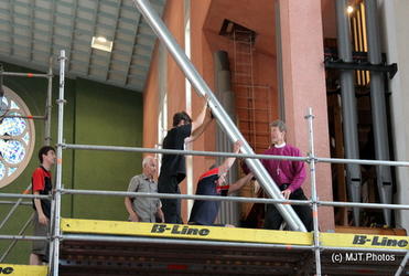 Bishop David Rice (right) braces to the task of installing a refurbished organ pipe. Photo: Margaret Thompson