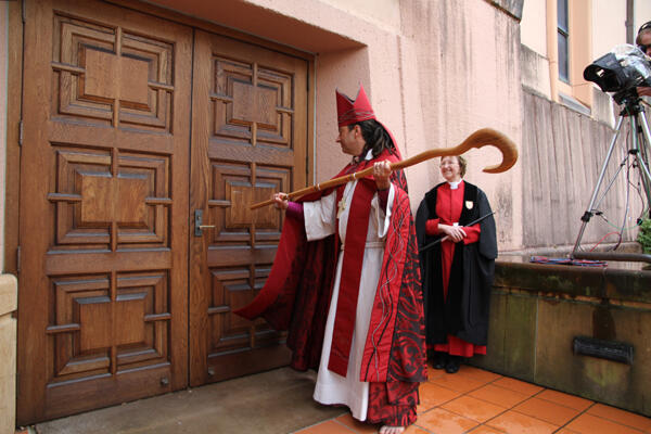 The new bishop strikes The Canterbury Door three times before being led inside to his new cathedra.