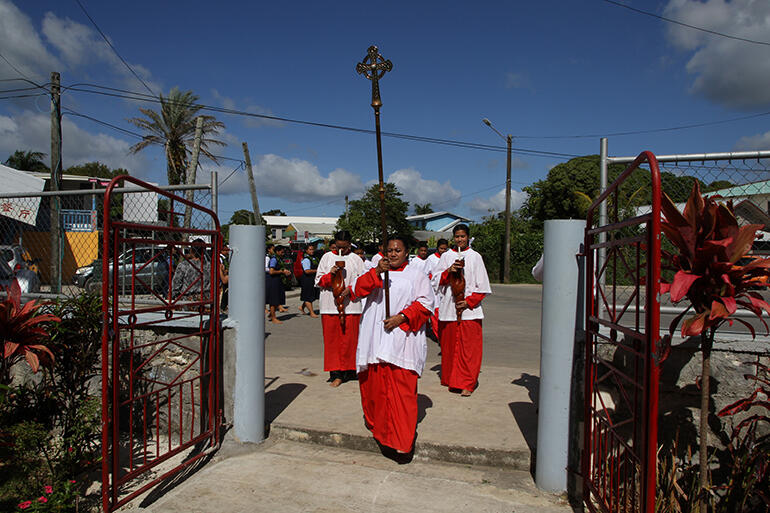 The procession turns in off the road into the church.