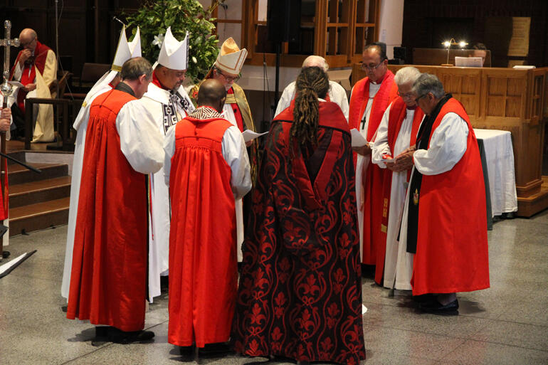 Bishops gather around Bishop-elect Ana in preparation to lay on hands in ordination. 