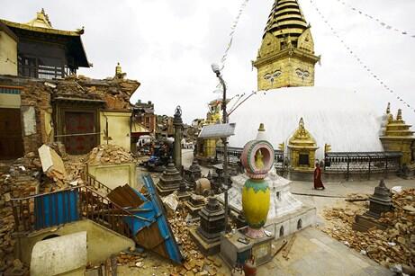 A monk walks amid the collapsed monastery and shrines at Swoyambhunath Stupa, a UNESCO world heritage site, 