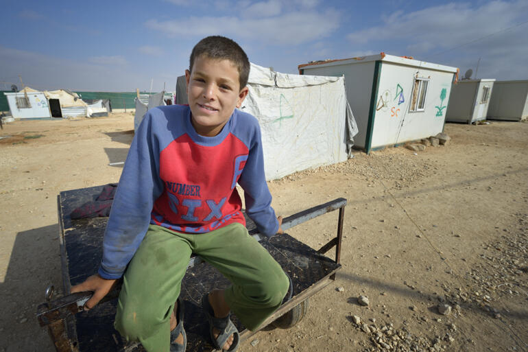 A young Syrian smiles from inside a Jordanian refugee camp in 2015. CWS has launched a fundraising challenge to live on refugee rations.