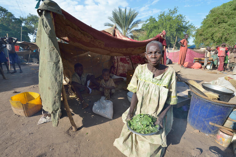 In an Episcopal church compound in Sudan, Araj shows the wild leaves, or 'hunger food' she has to feed her family. © ACT/Paul Jeffrey.