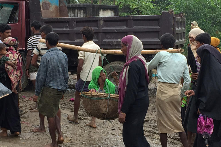 A Rohingya family flees on foot carrying an elderly relative. Photo:Christian Aid.