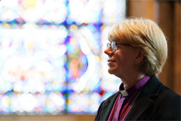 Bishop Sarah Mullally stands in profile before a stained glass window