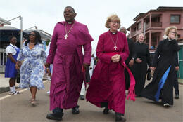 The Archbishop of Canterbury, Sarah Mullally, walks with the bishop of Asante Mampong, Cyril Kobina Ben-Smith, on a rammed-dirt street in Mampong, Ghana