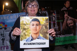 A protestor holds a photograph of Palestinian Christian boy facing 32 months in Israeli jail