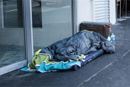 A person sleeps concealed under bedding on an NZ street