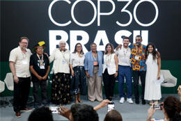 Faith leaders stand arm in arm before a COP30 banner