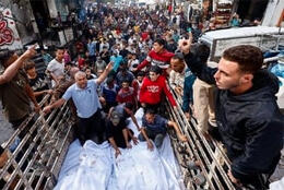Dead bodies wrapped in white body bags lie in a truck as a crowd of Palestinians gather