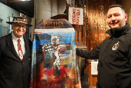 A new cope with a modern design featuring a crucifix and expressive colours is held between an Indigenous Australian Anglican elder and Māori Anglican rangatahi ministry leader Levi Torrey
