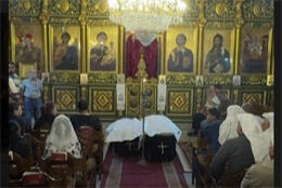 Two coffins with fabric palls sit before an ornate icon covered screen in Saint Porphyrius Orthodox Church in Gaza