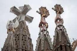 three towers topped with ornate sculpted crosses stand against a white sky