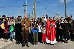Chinese and European Anglicans wave as a group surrounding their red-robed priest