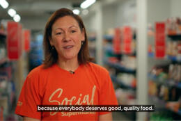 Three people walk along a small supermarket aisle