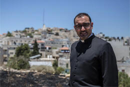 A Palestinian Catholic priest stands with the view of his Christian town in the West Bank