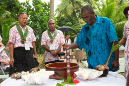 A group of pacific church leaders join Togoru community rep Barney Dunn around a cross and kava bowl as he lights a candle 