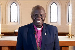 Sudanese Bishop in purple shirt and collar smiles at the camera