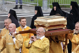 Men in gold vestments carry a golden reliquary box as nuns in long flat-topped habits walks alongside