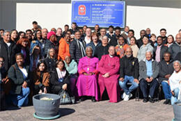 A large group people with two African bishops at the centre line up for a photo