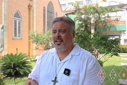 Archbishop Don stands before a pale orange-pink church in Brazil 