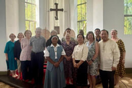 Anglican clergy and lay people gather for a group shot in a plain room
