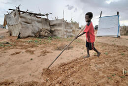 A small Sudanese child plays outside a makeshift dwelling