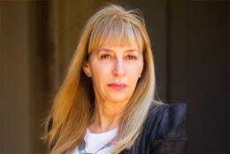 A middle-aged blond female neuroscientist looking directly into the camera