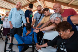 A group of Christians pray and lay hands on a man