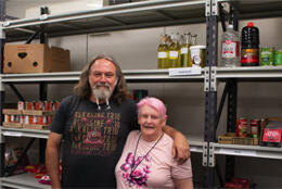 Two people stand amidst emptying shelves of food