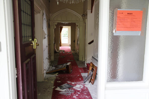 A glance inside the front door. Note the damaged wall plaster - and the official 'unsafe' sticker on the glass.