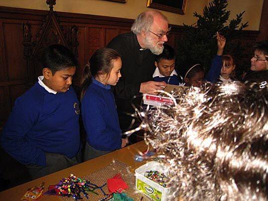 Dr Rowan Williams digs out the tinsel to decorate the Lambeth Palace Christmas tree, aided by children from Bonneville primary school, Clapham.