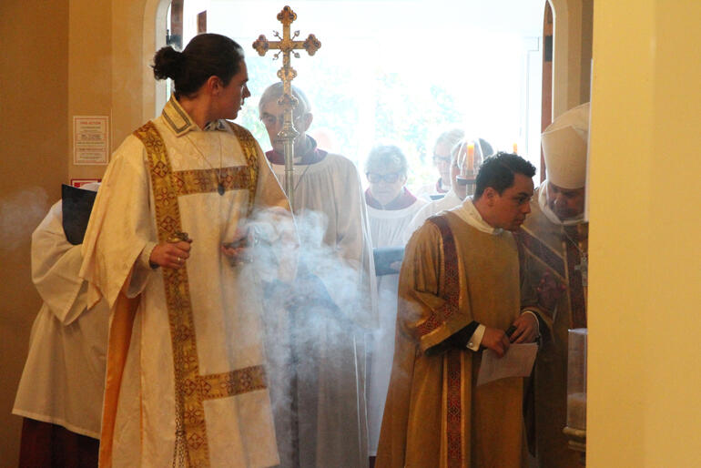 Clergy and servers gather at the Cathedral door surrounded by incense before the mass.