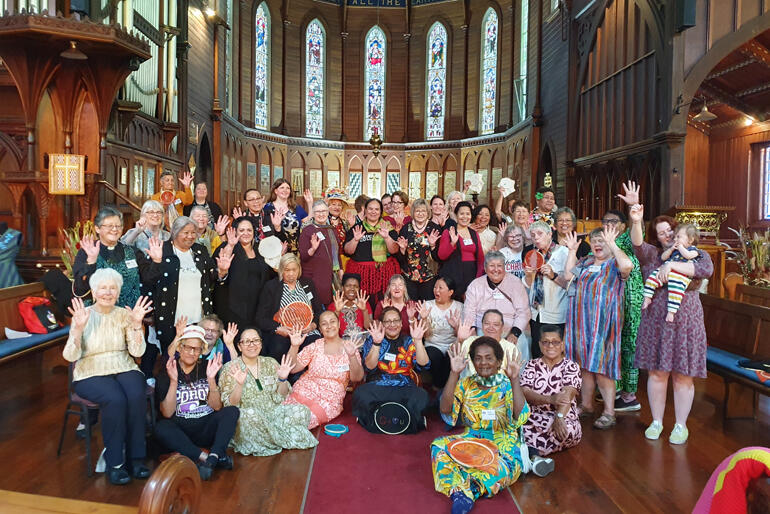 Women raise their hands to echo the 'Many Hands' theme of the AWSC 2023 Hui. Image: Ceridwyn Parr