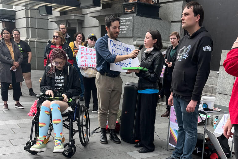A disability community activist speaks out against Government disability cuts at a protest at Auckland's Britomart transport hub, 8 Sep '24. A disability community activist speaks out against Government disability cuts at a protest at Auckland's Britomart transport hub, 8 Sep '24.