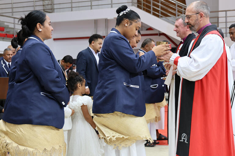 Bishop Andrew Hedge and Bishop Ross Bay serve communion to members of the Diocese of Polynesia choir.