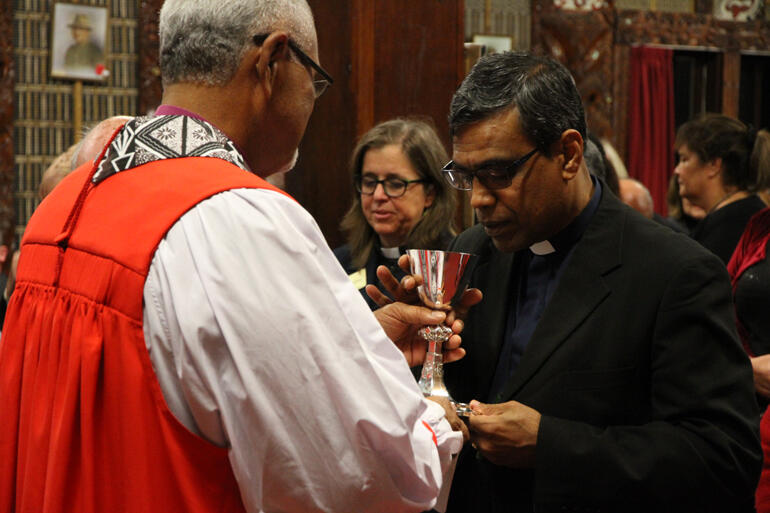 Bishop Henry Bull offers the chalice to Aotearoa-New Zealand Methodist President Rev Prince Devanandem.