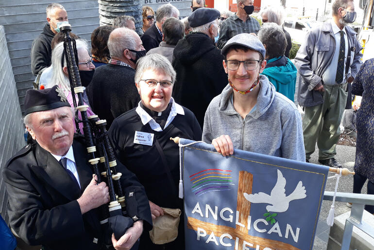 Anglican Pacifist Fellowship's Ven Indrea Alexander and Ollie Alexander stand with Pipe Major Bill Swift who piped open the event.