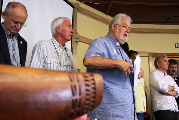 Rev Tom Van Culin, from Hawaii, reports from the men's caucus. Ian Sparks (left) and John Rea (both from the UK) stand in support.