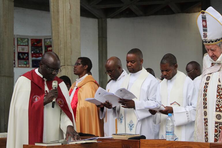 Bishop John prays alongside priests at Lusaka Cathedral.