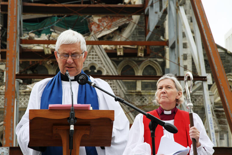 With the shattered west wall of the cathedral as a backdrop, Dean Peter Beck gives his mihi to the mourners.