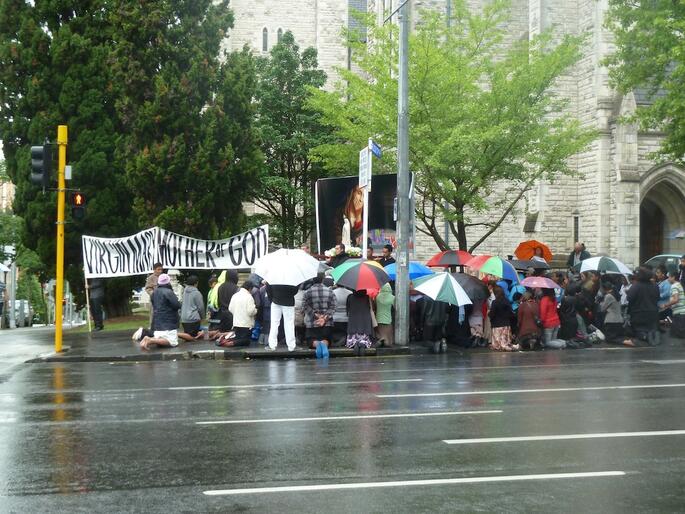 Billboard protesters kneel in prayer outside St Matthew-in-the-City.