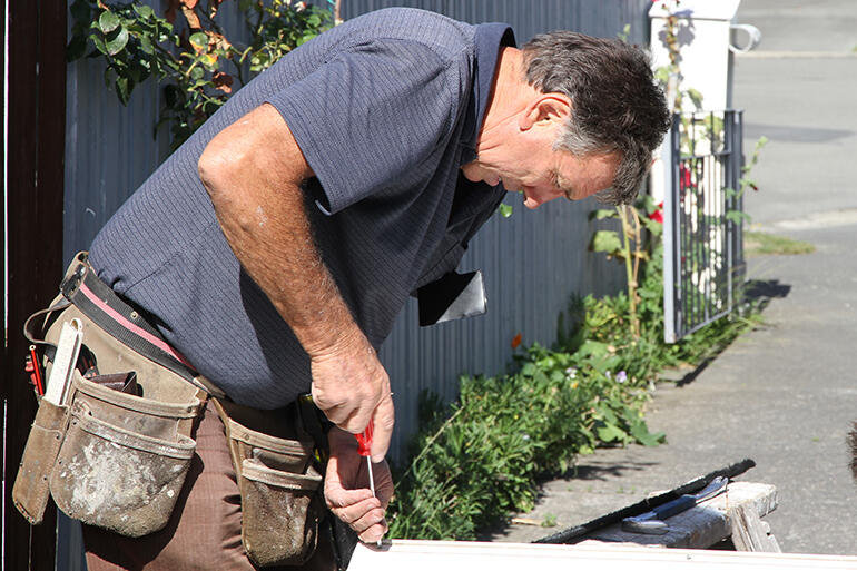 Men at work: Geoff Bennett, from COTS, Blockhouse Bay, fixing one more jammed Aranui door.