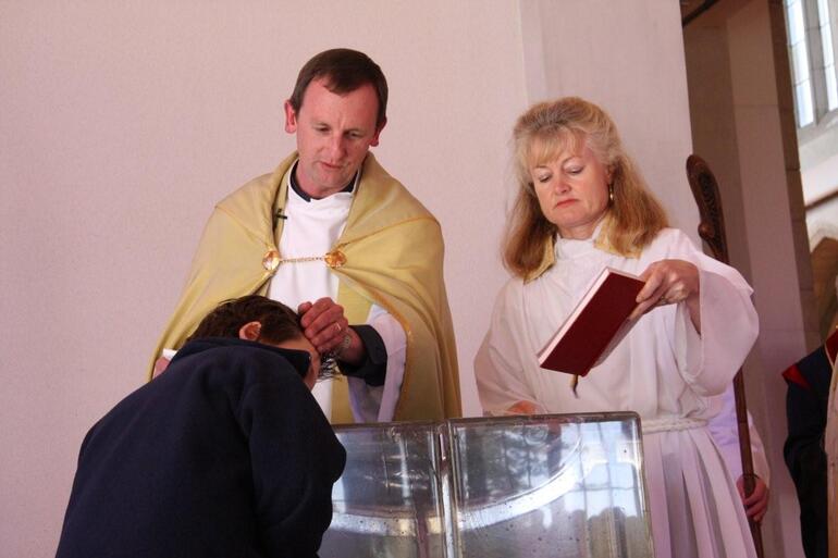 Dean Ross performs the first baptism at Holy Trinity Cathedral's new glass baptismal font.