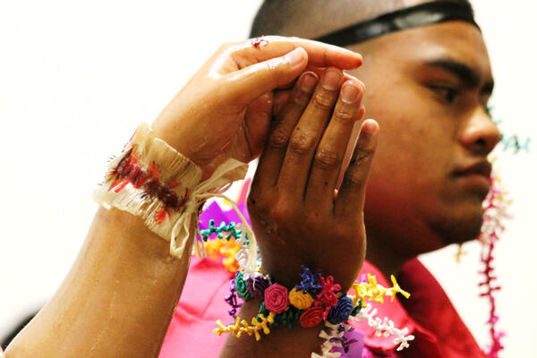 Manase Tu’ilotolava, arms glistening with oil and wrists garlanded with colour.